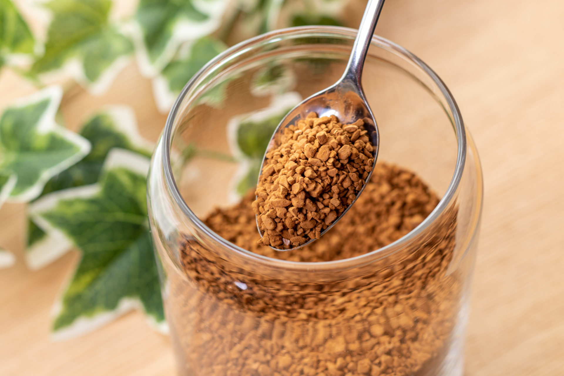 ガラス容器に入ったインスタントコーヒーをスプーンですくっている