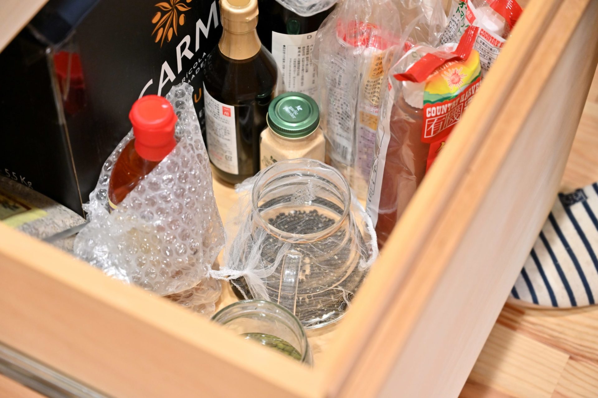 もやしの種を入れたガラス容器を棚にしまっている