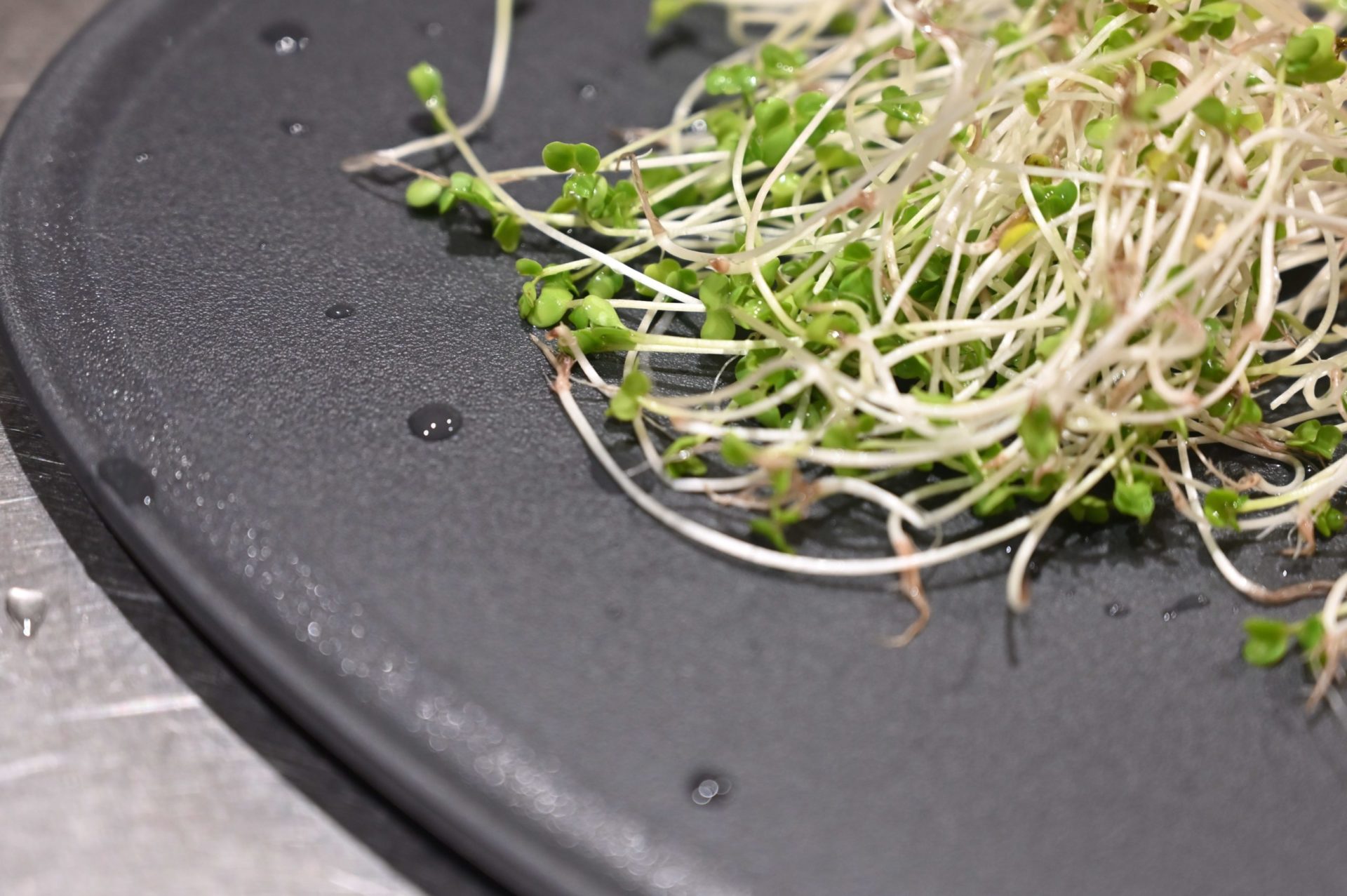 黒いまな板に置かれたかいわれ