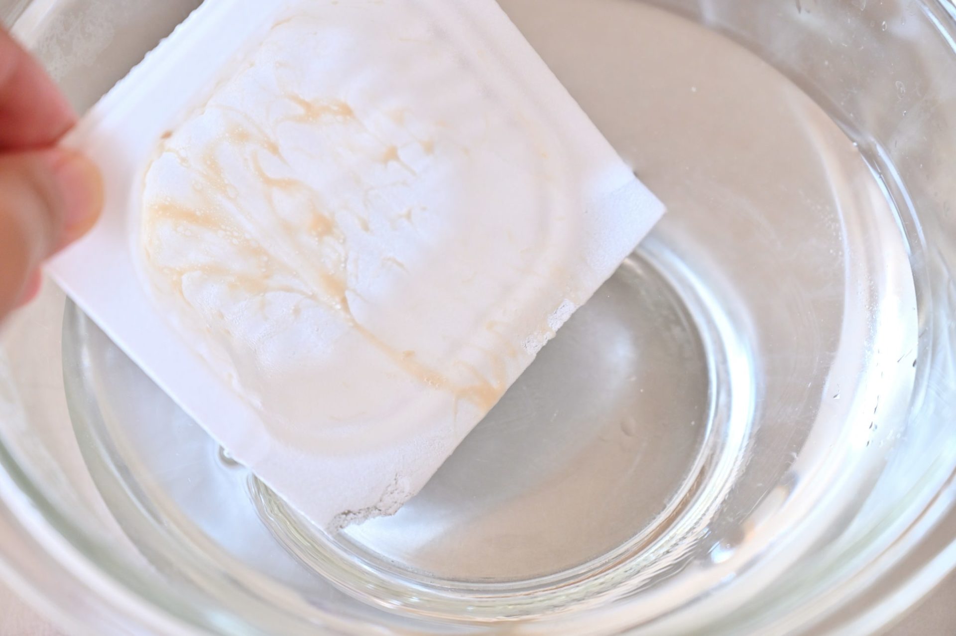 水を張ったボウルに納豆の容器を入れている